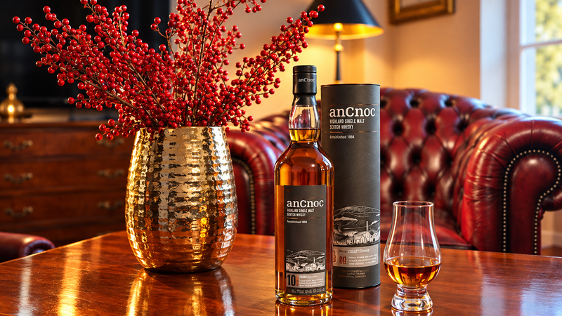 Whisky anCnoc Peated 10y s tubusem a sklenkou na stole v salonku